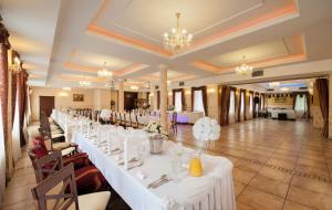 比亚韦斯托克Hotel POD HERBEM -POKOJE OZONOWANE的宴会厅的一排桌子,上面有白色的桌子设置