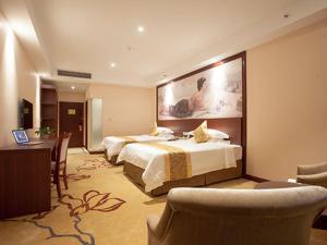 杭州维也纳酒店杭州半山石桥路店的酒店客房带两张床、一张桌子和椅子。