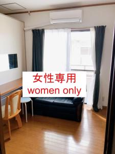 大阪HOSTEL198 Female only dormitory cabin typeーVacation STAY68067v的一间设有黑色沙发和窗户的客房