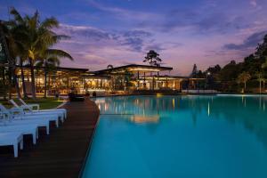 拉古洼Natra Bintan, a Tribute Portfolio Resort的一座带椅子的游泳池,一座夜间建筑