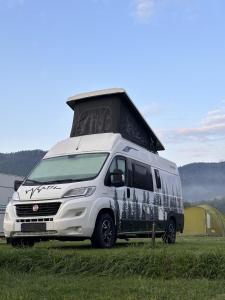 拉德库夫Góry Stołowe Camp -miejsce na kamper, przyczepę lub namiot的停在田野上的白色货车,车顶上