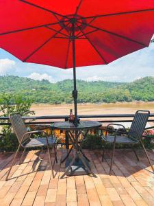 琅勃拉邦Luang Prabang Mekong Charm River View的一张桌子和椅子,配有红色雨伞