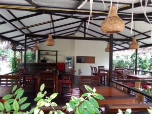 象岛幸运壁虎花园旅馆的餐厅设有木桌、椅子和吊灯