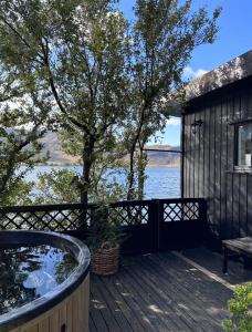 莫斯费德斯拜尔Cosy lakeview cabin 45 minutes from Reykjavik的树旁甲板上的热水浴池