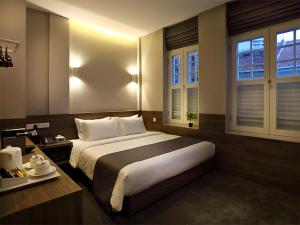 新加坡Arcadia Hotel的一间卧室设有一张大床和两个窗户。