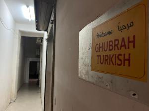 马斯喀特Ghubrah Turkish male hostel Muscat的走廊边的标志,墙上有标志