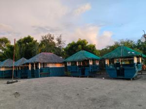 CabaSeaside Sunset Beach Resort的海滩上一排带绿色屋顶的小屋