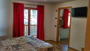 尚波吕克尼德艾格勒旅馆的一间卧室配有红色窗帘、一张床和窗户