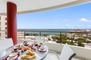 努美阿Ramada Hotel & Suites by Wyndham Noumea的阳台上的餐桌和食物,享有海景