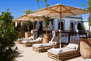 马拉喀什达尔阿尔法拉摩洛哥传统庭院住宅酒店的庭院里摆放着一排椅子和一把遮阳伞