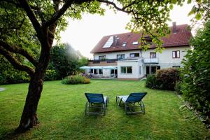 穆尔海姆施赫尔伽尼酒店的两把椅子坐在房子前面的草上