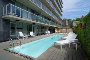 渥太华SOHO Residences Lisgar的一座带白色椅子的游泳池和一座建筑