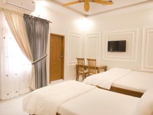 卡拉奇Stay Inn Hotel Rooms Karachi - Gulshan - Agha Khan Hospital - Airport的一间卧室配有两张床、一张桌子和一台电视。