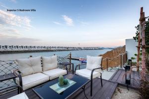 富查伊拉Al Dana Paradise Luxury Villas Palm Fujairah Sea View的阳台的天井配有沙发和椅子