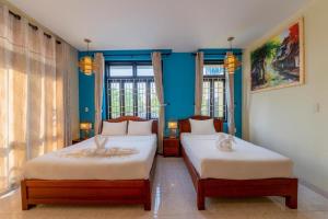 会安Hoi An Heart hostel Villa的配有两张床铺的蓝色墙壁和窗户