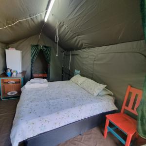 格拉斯科普Chosen Glamping Tents的一间卧室配有一张床铺,帐篷内提供一把椅子