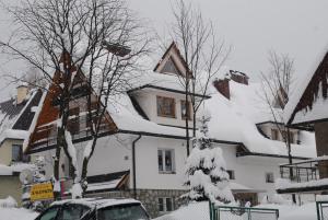 扎科帕内Studia "U Tomasza"的一座雪覆盖的房子,前面有一辆汽车停放