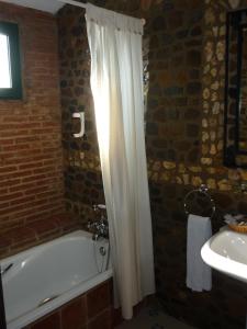 Encinasola林孔阿贝德酒店的浴室设有白色的淋浴帘、浴缸和水槽。