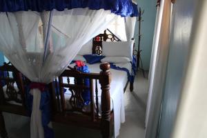 桑给巴尔萨尔姆公主宾馆的卧室配有带白色窗帘的天蓬床