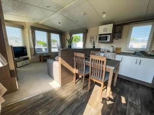 大雅茅斯Lovely 6 Berth Caravan With Decking At Cherry Tree Park In Norfolk Ref 70320C的厨房以及带桌椅的起居室。