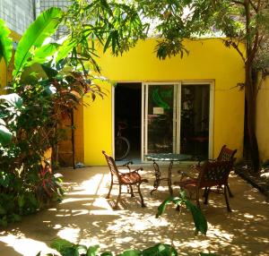 海口海口巴纳纳国际青年旅舍的黄色房子前面的庭院配有桌椅