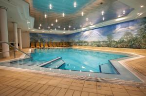 马格德堡热特斯瓦格酒店的墙上挂有壁画的大型游泳池