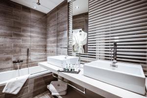 尚佩里Hôtel Le White - Le 42 Restaurant的浴室设有2个水槽、浴缸和镜子