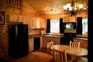 戴德伍德科尔山林小屋的厨房配有桌子和黑冰箱。