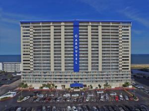 大洋城旋转木马度假公寓酒店 的停车场内停放汽车的大型建筑