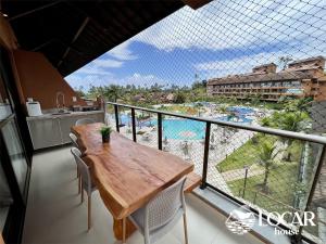 塔曼达雷Eco Resort Praia dos Carneiros - Flats & Bangalô - LocarHouse的阳台配有桌子,享有游泳池的景色