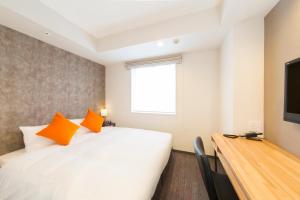 东京东急五反田住宿公寓式酒店的一间卧室配有带橙色枕头的床和电视。