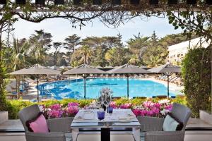 卡斯卡伊斯Palácio Estoril Hotel, Golf & Wellness的池畔露台配有桌椅