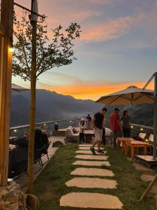 萨帕PHANSI - Glamping, View Point 360, Bar & BBQ的一群人站在石头人行道上,一边欣赏日落