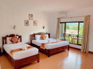 万荣Vang Vieng Hana River View Hotel & Travel的带阳台的客房内的两张床