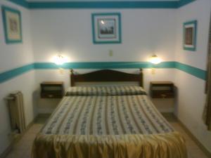 特雷斯阿罗约斯Hotel Plaza Tres Arroyos的卧室配有一张带两盏灯的墙壁床。