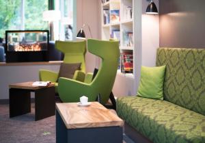 不莱梅Hotel Munte am Stadtwald的一间设有绿色椅子和桌子的等候室