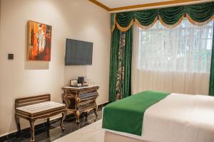 LimuruMuthu Sovereign Suites & Spa, Limuru Road, Nairobi的一间卧室配有一张床、一张书桌和一个窗户。