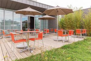 圣纳泽尔Appart'City Confort Saint-Nazaire Océan的木甲板配有桌椅和遮阳伞