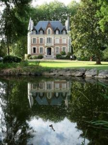 ContresMaison d'hôtes Le Manoir de Contres的水体中反射的大房子