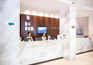 北海City Comfort Inn Beihai Beibu Gulf Golden Beach Underwater World的两名妇女在酒店大堂的柜台坐