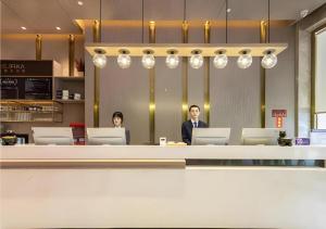 泉州Premier City Comfort Hotel Quanzhou Wanda Plaza的两个人坐在办公室的柜台