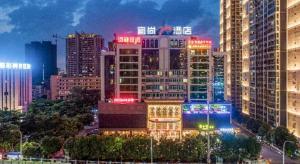 南宁Echarm Plus Hotel Nanning Convention and Exhibition Center Medical University的城市天际线,晚上有灯光建筑