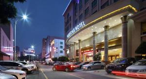 ShenzhenShenzhen Hanyong Hotel Fuyong Branch的商店前有车辆停放的城市街道