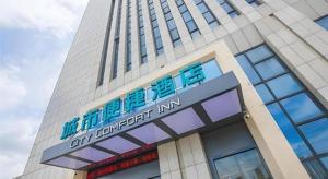 宣州区City Comfort Inn Xuancheng Wanda Qinglv Guoji的一座高大的建筑,前面有标志