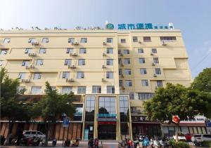 柳州City Comfort Inn Liuzhou Longtan Park Ma'anshan Baiyun的一座黄色的大建筑,前面有人站在