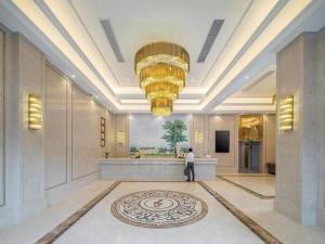 福州Vienna Hotel Fuzhou Mawei的站在大堂,有大吊灯的人