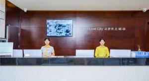 贵阳City Comfort Inn Guiyang Yan'an Middle Road Fountain Metro Station的两名妇女站在大厅的柜台上