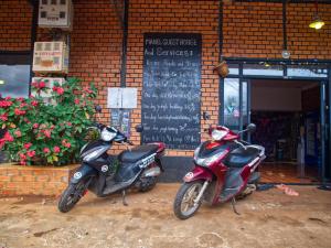 森莫诺隆Manel Guesthouse and Restaurant的停放在砖楼前的两辆摩托车