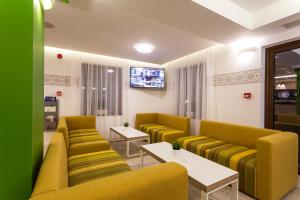 特里亚夫纳赞美酒店的一间设有黄色沙发和电视的等候室
