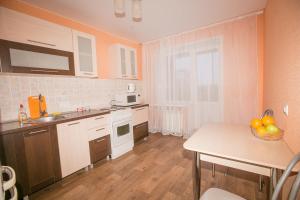 托木斯克Apartment On Kievskaya 90的厨房配有白色橱柜和一张带一碗水果的桌子